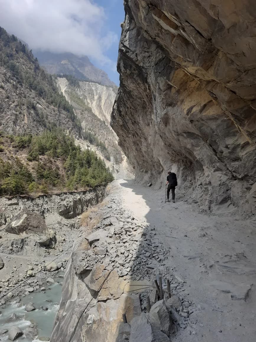 A narrow trail traversing a steep eroded hillside high above a valley