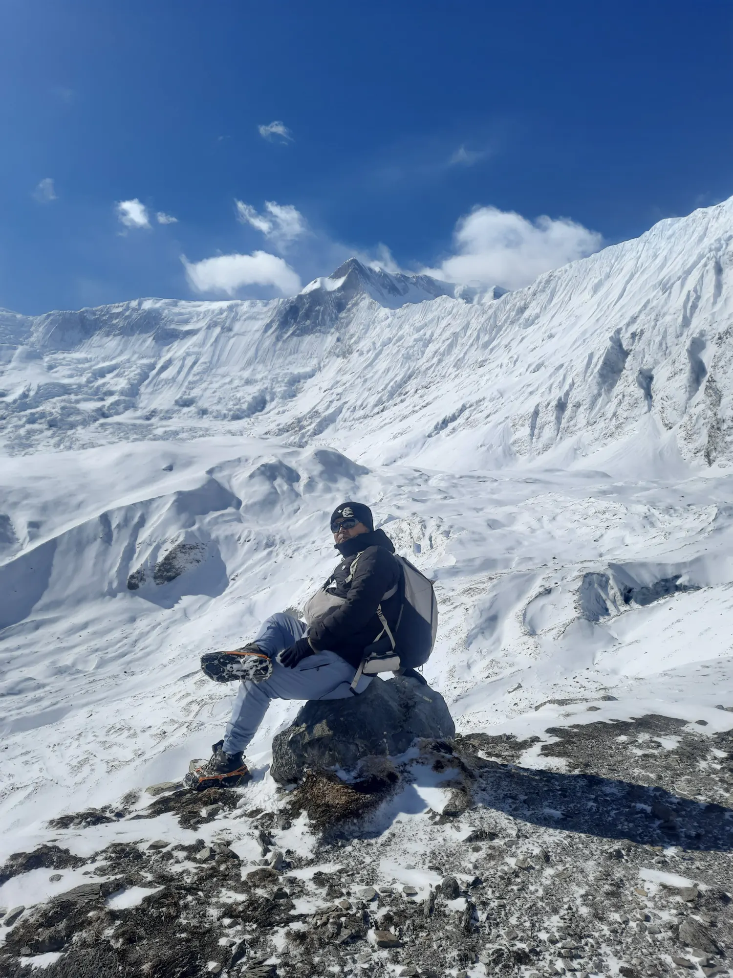Trekker resting in a high snow basin surrounded by glaciated peaks