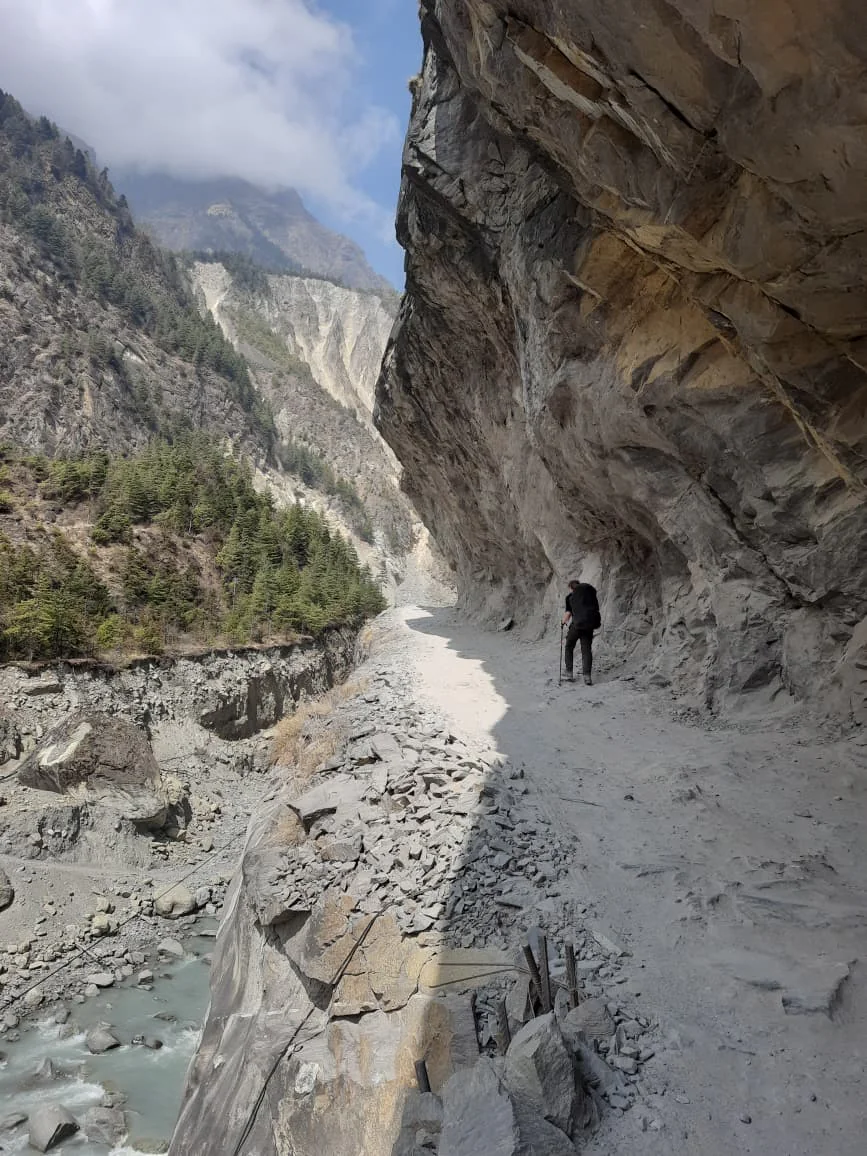 A narrow trail traversing a steep eroded hillside high above a valley