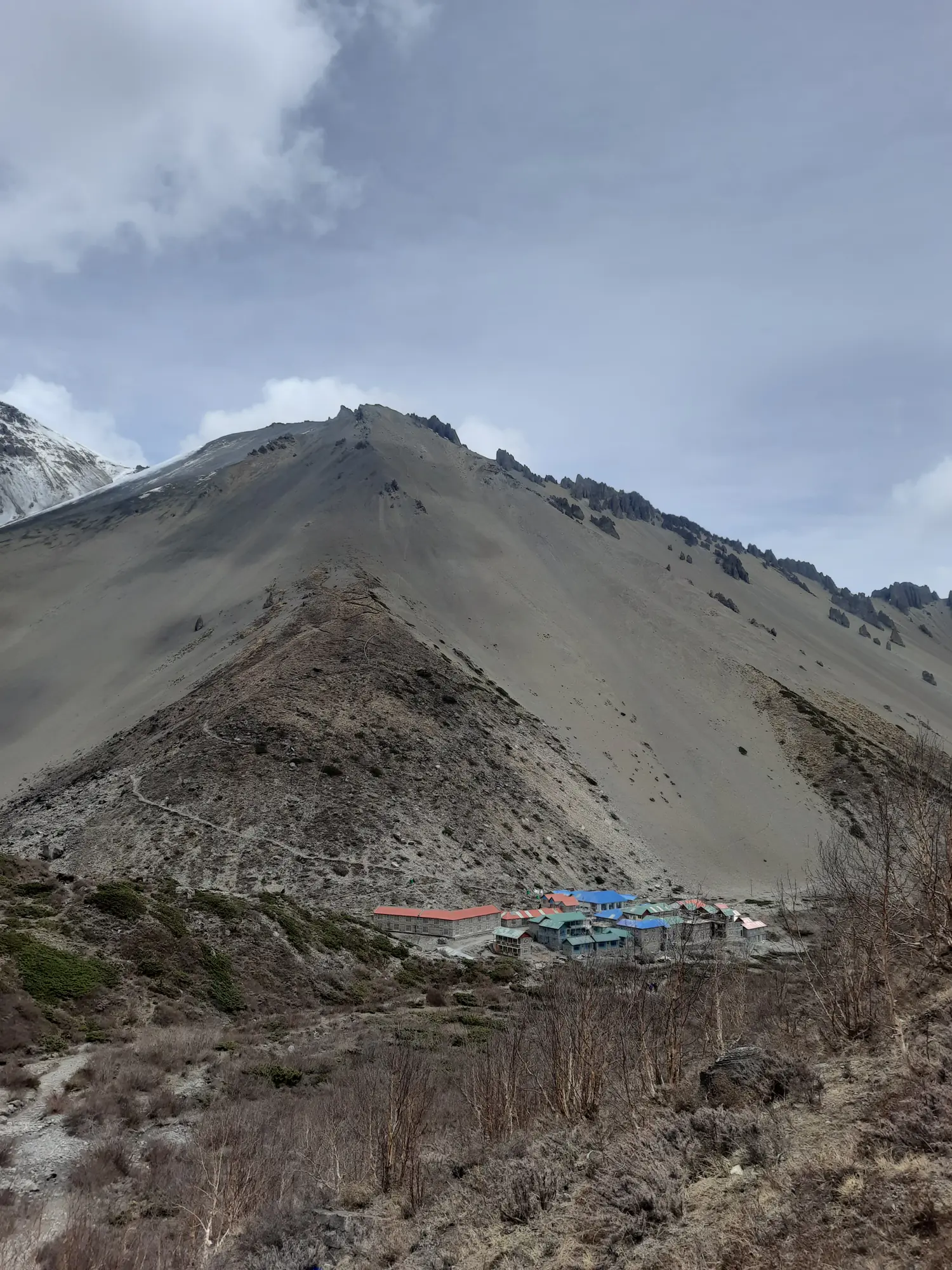 A cluster of teahouse lodges under a bare high ridge on the upper circuit
